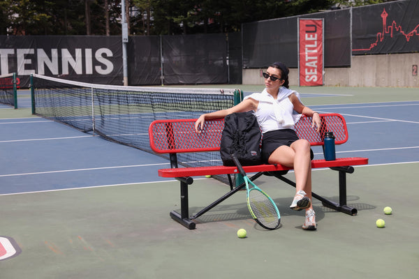 A person sitting beside a Smart Alec 2.0 at a tennis court.